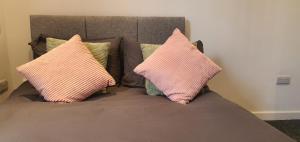 two pink pillows sitting on top of a bed at Leicester City Apartments in Leicester