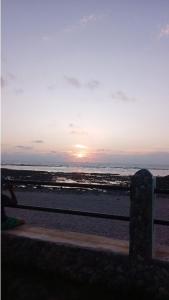 einen Sonnenuntergang am Strand mit dem Ozean im Hintergrund in der Unterkunft Appartement confortable en bord de la mer in Pont Blondin