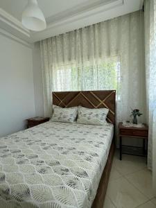 Schlafzimmer mit einem Bett und einem Fenster mit Vorhängen in der Unterkunft Appartement confortable en bord de la mer in Pont Blondin