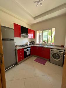 eine Küche mit roten Schränken, einer Waschmaschine und einem Trockner in der Unterkunft Appartement confortable en bord de la mer in Pont Blondin