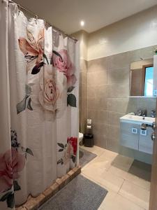 ein Badezimmer mit einem Duschvorhang mit Rosen darauf in der Unterkunft Appartement confortable en bord de la mer in Pont Blondin