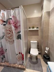 ein Badezimmer mit einem WC und einem Duschvorhang mit Rosen in der Unterkunft Appartement confortable en bord de la mer in Pont Blondin