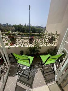 zwei grüne Stühle auf einem Balkon mit Topfpflanzen in der Unterkunft Appartement confortable en bord de la mer in Pont Blondin
