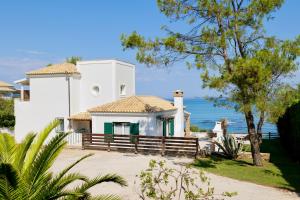 une maison blanche avec l'océan en arrière-plan dans l'établissement Beachfront Villa Dionysos - With private beach, à Sidari
