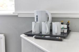 una bandeja con tres tazas blancas y un mando a distancia en Properties Unique Dene Rooms - Family Room, en Newcastle