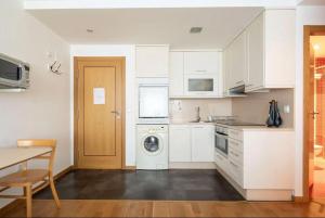 a kitchen with white cabinets and a washer at Apartamento Centro de Baiona con Parking in Baiona