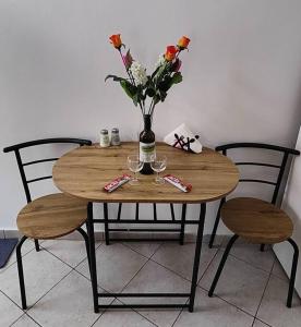 a wooden table with a vase of flowers and two chairs at Panos & Maria studio! in Kalamata