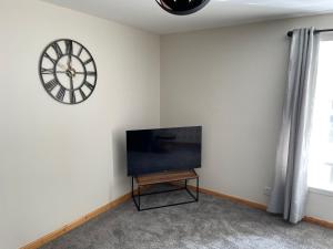 a living room with a tv and a clock on the wall at 3 Bedroom Townhouse on NC500, Wick, Highland in Wick