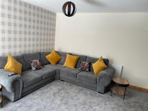 a living room with a gray couch with yellow pillows at 3 Bedroom Townhouse on NC500, Wick, Highland in Wick