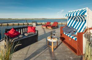 a deck with couches and an umbrella and a table at Hausboot Isa-Bella in Burg