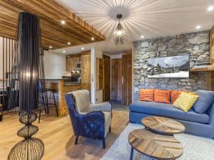 a living room with a blue couch and a stone wall at Appartement luxe avec wifi et parking sur les pistes au cœur de Val-d'Isère - FR-1-694-133 in Val dʼIsère