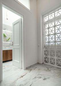 an open door in a bathroom with white walls and marble floors at The Aeolian in Athens