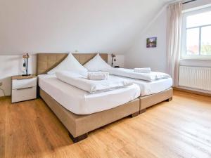 twee grote bedden in een kamer met houten vloeren bij Backbord in Greetsiel