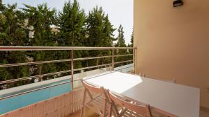 uma mesa branca e cadeiras numa varanda com árvores em Luminous 2 BDR Apartment W/Pool by LovelyStay nos Olhos de Água