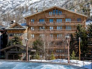 a large wooden building with a snow covered mountain at Appartement luxe 4 pièces + studio, terrasse Sud, centre Val-d'Isère, 2023, 8 personnes - FR-1-694-149 in Val dʼIsère