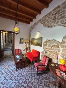a living room with red chairs and a stone wall at Locanda Sette Fate SPA e Solarium in Palermo