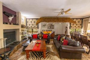 a living room with leather furniture and a fireplace at Eden Safari Country House in Marloth Park