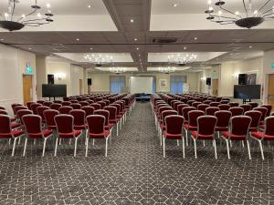 una grande stanza con sedie e schermi di Delta Hotels by Marriott Milton Keynes a Milton Keynes