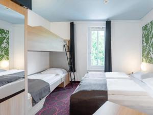 a hotel room with two beds and a window at B&B Hotel Offenburg in Offenburg