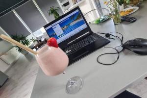 uma bebida num copo sentado numa secretária com um computador portátil em La Maisonette 