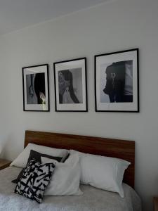 uma parede branca com quatro quadros acima de uma cama em Lux Domus em Montoro Inferiore