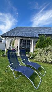 寇帕利諾的住宿－Rodzinne miejsce，两把蓝色椅子坐在房子前面的草上