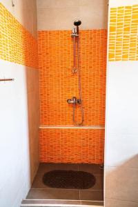 uma casa de banho com um chuveiro e uma parede em azulejos laranja em Kampanjola em San Lawrenz
