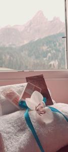 a bed with two books and a flower on it at Excelsior Hotel Cimone LowCost in San Martino di Castrozza