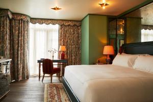 a bedroom with a bed and a desk and a window at The Fifth Avenue Hotel in New York