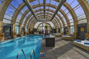 an indoor pool with an arched glass ceiling and a swimming pool at The Ritz-Carlton, Santiago in Santiago