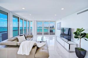 a living room with a couch and a television at Feels Like Summer ~ Panoramic Water Views! in Miami
