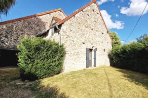 un vieux bâtiment en briques avec un bush devant lui dans l'établissement Gîte de charme climatisé au coeur de l'Auxois, à Essey