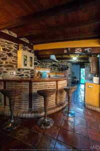 uma cozinha com dois bancos de bar e uma parede de pedra em Casa rural la corva em Triollo