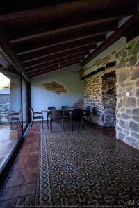 a patio with tables and chairs and a stone wall at Casa rural la parda in Triollo