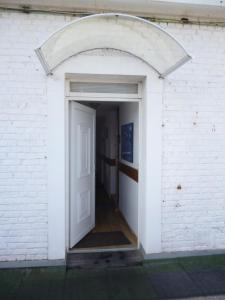 een ingang naar een wit bakstenen gebouw met een open deur bij Gentlemen appartement au premier étage à 50 metres de la mer in Sangatte