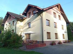 a large white house with a table and an umbrella at Apartament Górski Lux in Krynica Zdrój