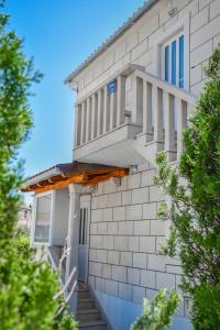 ein weißes Backsteingebäude mit einer Veranda und einer Treppe in der Unterkunft Apartments Sena in Bol