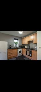 uma grande cozinha com armários de madeira e uma máquina de lavar louça em Glasshoughton Platinum em Castleford