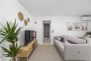 Terracos de Quarteira II Purple by Real Properties في كوارتيرا: غرفة معيشة مع أريكة وتلفزيون