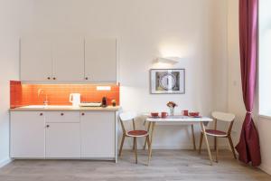 uma cozinha com armários brancos e uma mesa com cadeiras em Hungarikum Studios em Budapeste