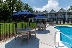 a patio with tables and umbrellas next to a pool at Hotel Manteo in Manteo