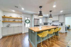 a kitchen with a large island with yellow bar stools at Central Tulsa Cottage with Yard about 3 Mi to Downtown! in Tulsa