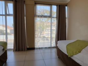 a bedroom with two beds and a large window at Cube Hotel in Durban