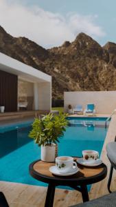 a table with two cups on it next to a pool at Jeema lodge in Hatta