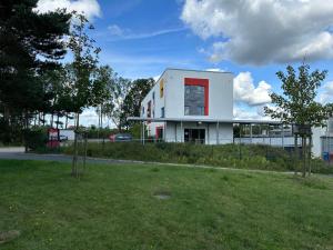 a white building with a red door in a field at Serways Hotel Lüneburger Heide West in Behringen