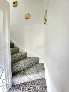 a stairway with grey carpeting and a stair case at Quirky Home, Quiet Neighbourhood in Newton Mearns