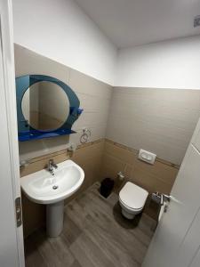 ein Badezimmer mit einem Waschbecken, einem WC und einem Spiegel in der Unterkunft H&A Guest House in Divjaka