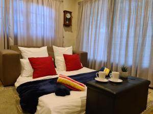 a bedroom with two beds with red pillows and a table at Firefly Cottage: Cosi nest tucked away in garden in Kenton on Sea