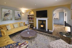 a living room with a yellow couch and a fireplace at Middleton Farmhouse in Inverness