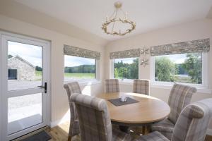 a dining room with a table and chairs and windows at Middleton Farmhouse in Inverness
